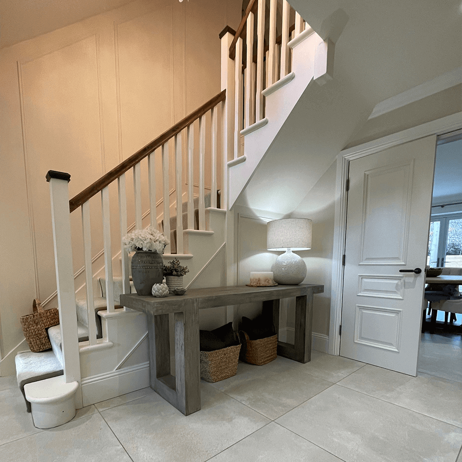White staircase leading up to a landing with wooden table underneath